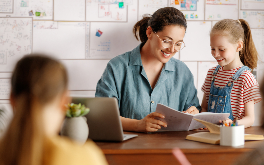 Student with a teacher at the teacher's desk