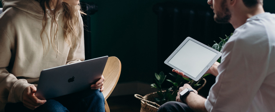 A student with a laptop and a student with an iPad having a conversation