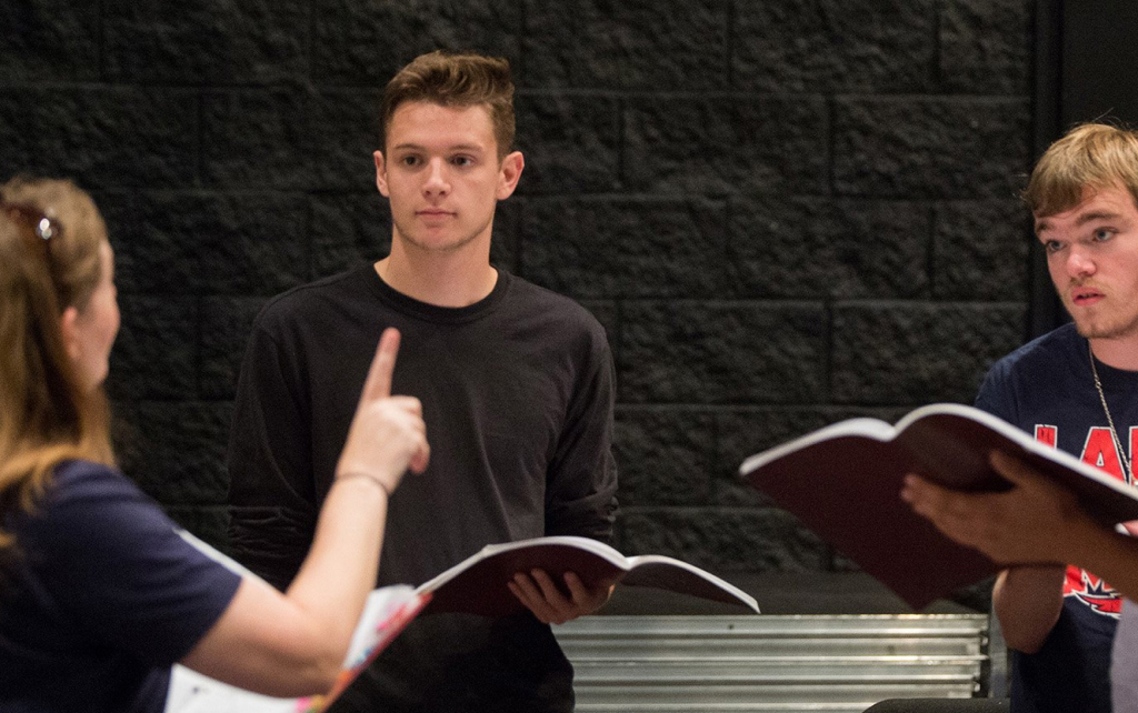 Theatre teacher and students reading scripts