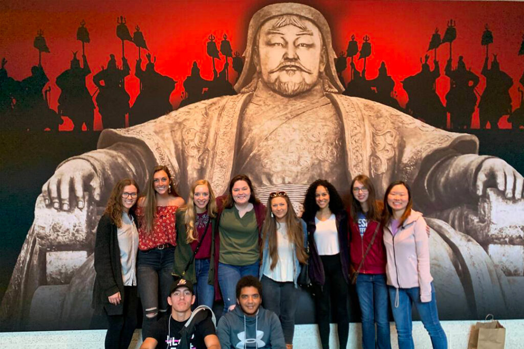 Group of students posing in front of a mural