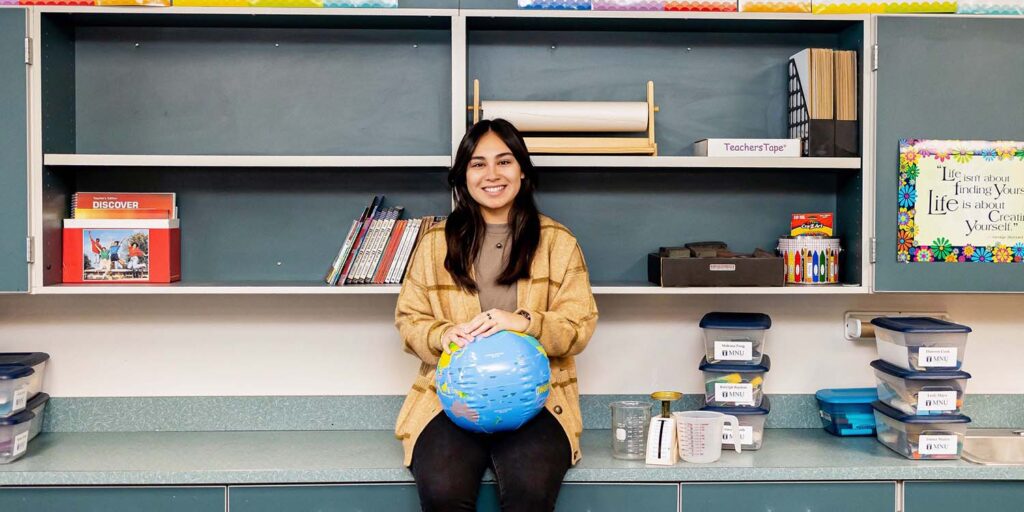 Female teacher ed student in classroom holding a globe