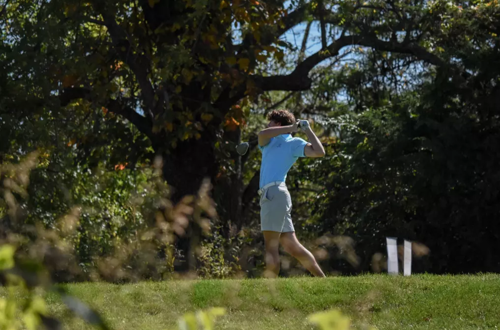 MNU Student at a golf tournament swinging a golf club